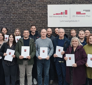 20 Kolleginnen und Kollegen aus kommunalen und staatlichen Behörden mit ihren Zertifikaten der überfachlichen Qualifizierung für das Statusamt A11 vor dem Lehrgebäude der HöV Rheinland-Pfalz in Mayen.