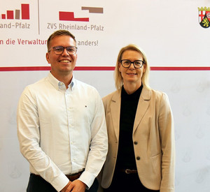 Direktorin Alice Schmidt und Referent Julian Schmitz stehen vor der Pressewand der Hochschule für öffentliche Verwaltung Rheinland-Pfalz bei der Infoveranstaltung zur Beihilfe.