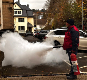 Mitarbeiter der Firma Feuerschutz Kürten während der Vorführung eines Pulver-Feuerlöschers.