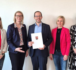 Fünf Personen stehen nebeneinander und schauen in die Kamera. In der Mitte steht Andreas Mattlener, der zu seinem 25-jährigen Dienstjubiläum im öffentlichen Dienst offiziell geehrt wird. Mit auf dem Foto sind Waltraud Leich, Alice Schmidt, Sandra Hering und Jennifer Junk.