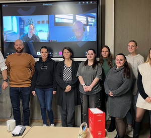 Studierende der HöV RLP und Dozent Christoph Buttner in einem Seminarraum der HöV RLP, auf einem Bildschirm sind die digital zugeschalteten Richter Mats Becker und Maximilian Rutz zu sehen.